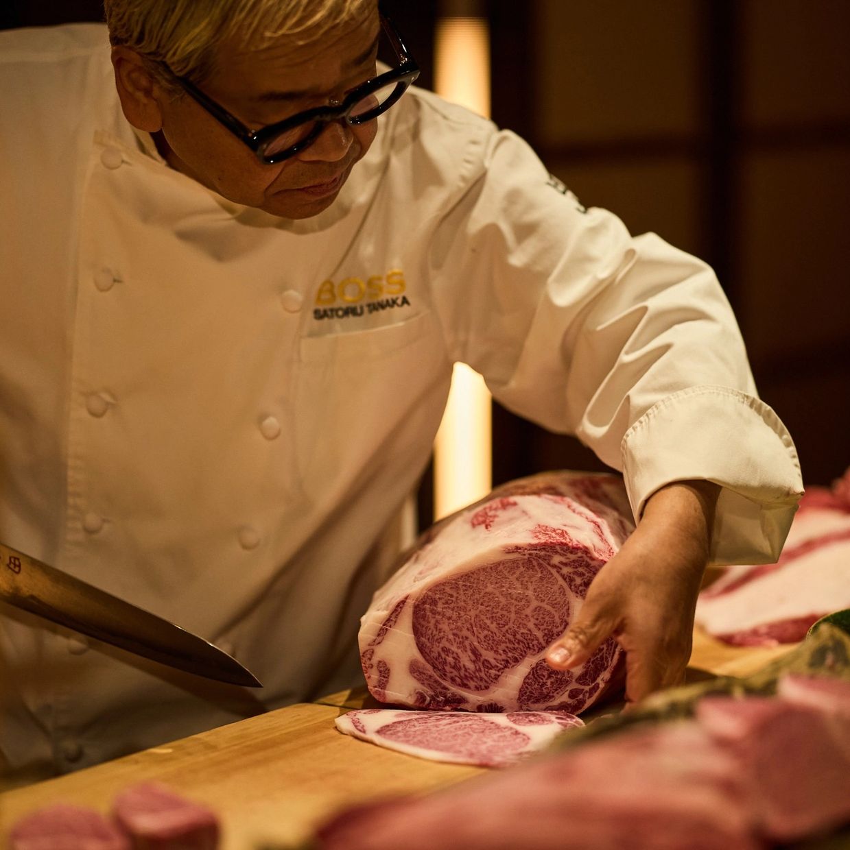 Chef slicing premium marbled beef with precision in a warm kitchen.