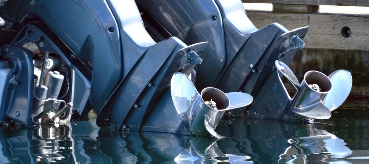 Two boat propellers partially submerged in water.