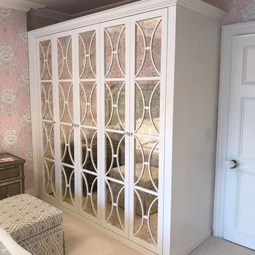 Elegant mirrored wardrobe with intricate white lattice design in a floral-themed bedroom.