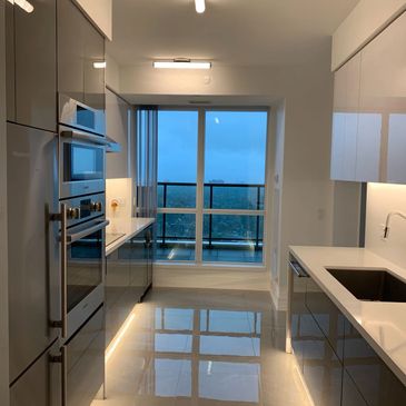 Modern kitchen with glossy cabinets and large window view.
