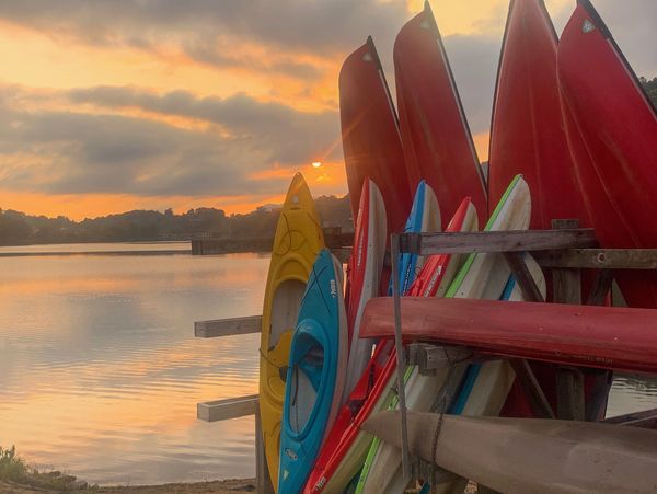 Colorful kayaks available for rent near Lake Junaluska, North Carolina, with lake in the background.
