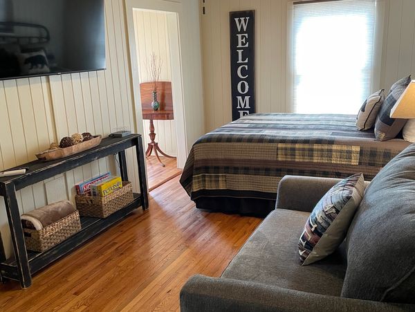 Lake Life Upper Apartment studio with queen bed, twin sleeper sofa, TV, and seating area.