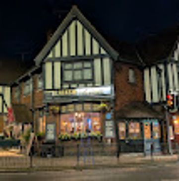 A traditional Tudor-style building lit up at night on a street corner.