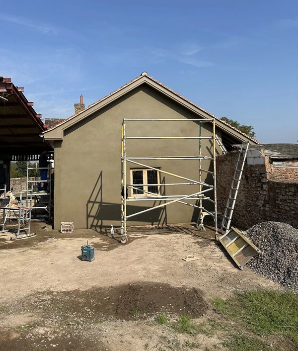 A house under construction with scaffolding and construction materials outside.