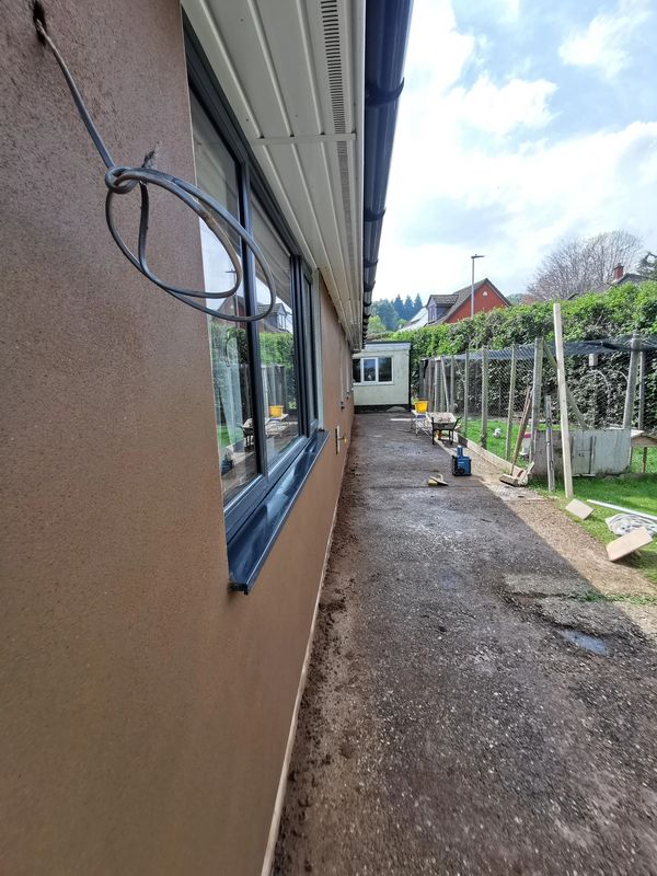 A narrow outdoor space alongside a building with construction materials scattered.
