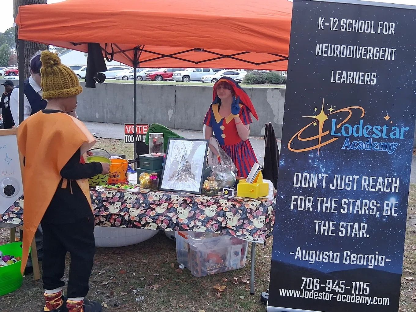 Outdoor booth promoting Lodestar Academy for neurodivergent learners with Halloween-themed decorations.