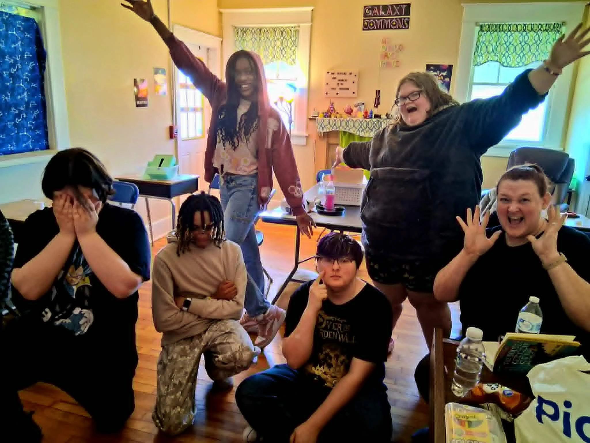 A joyful group of young people posing enthusiastically in a bright room.