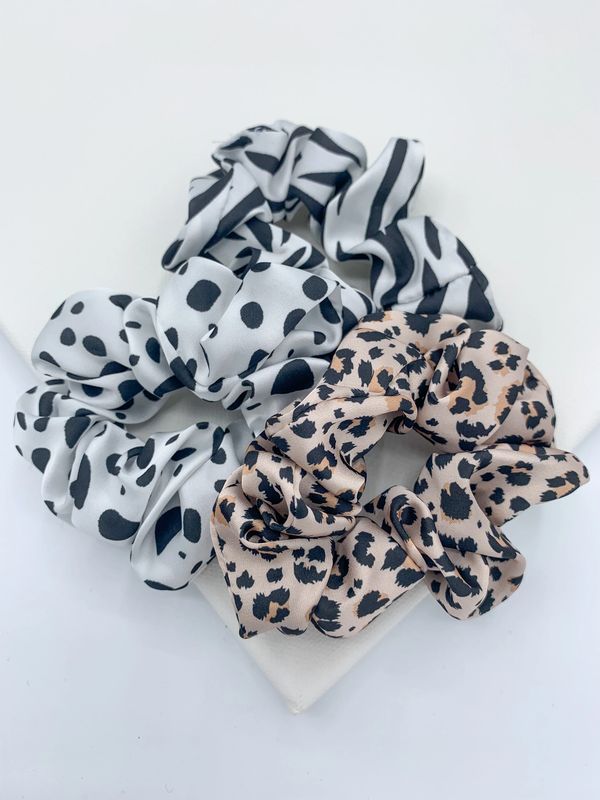 Three satin scrunchies in animal prints of zebra, leopard and dalmatian. 