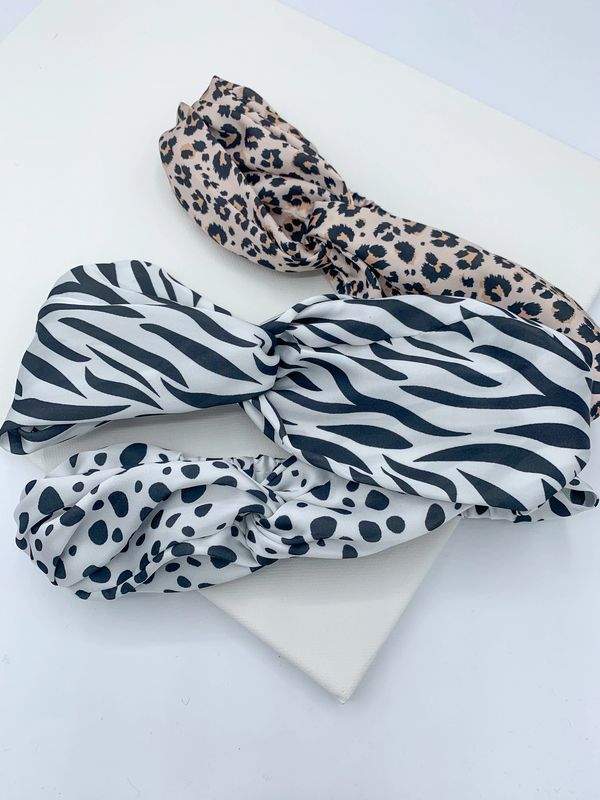 Three knotted fabric headbands in animal print. One zebra print, leopard print and dalmatian print.