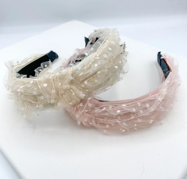 Two mesh spotty knotted headbands, one in pink and one in cream.