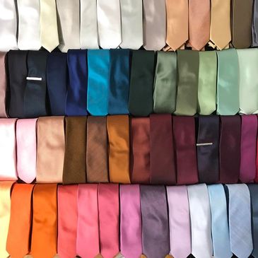 A variety of colourful shiny ties. Colours are in an ombre rainbow format next to each other. Colour