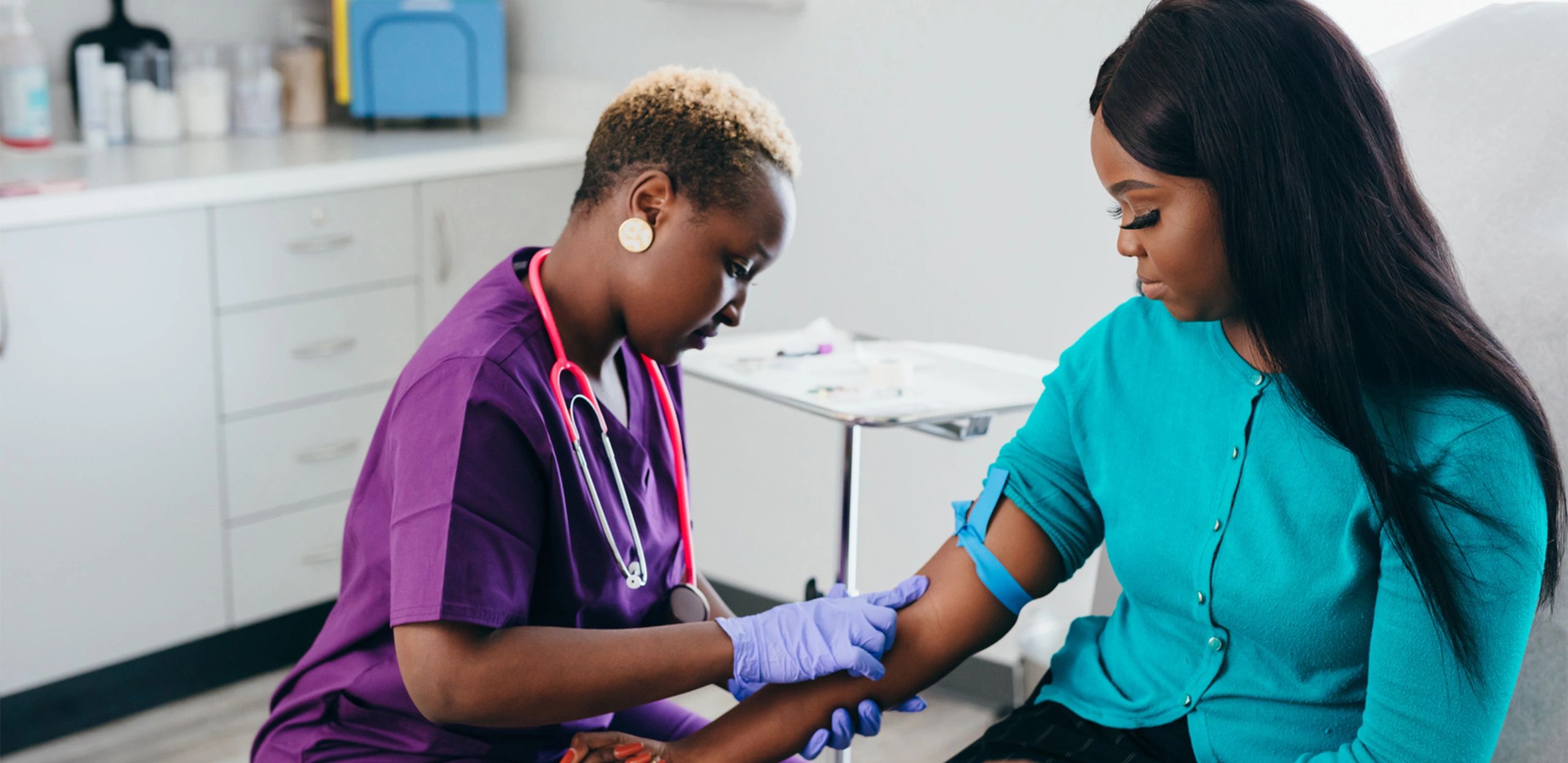 Nurse preparing a patient for a blood draw in a clinical setting.