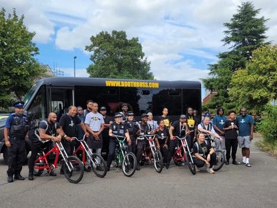 Group of people and police officers with bikes posing in front of a bus.