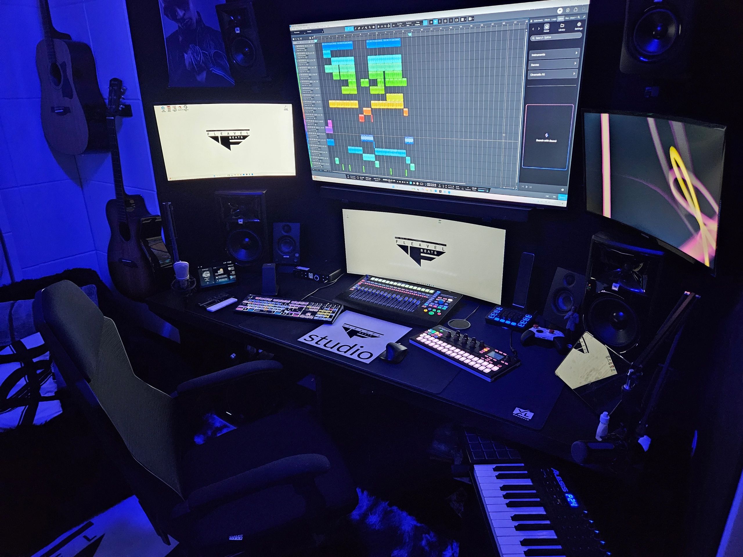 Music production studio with multiple monitors and instruments.