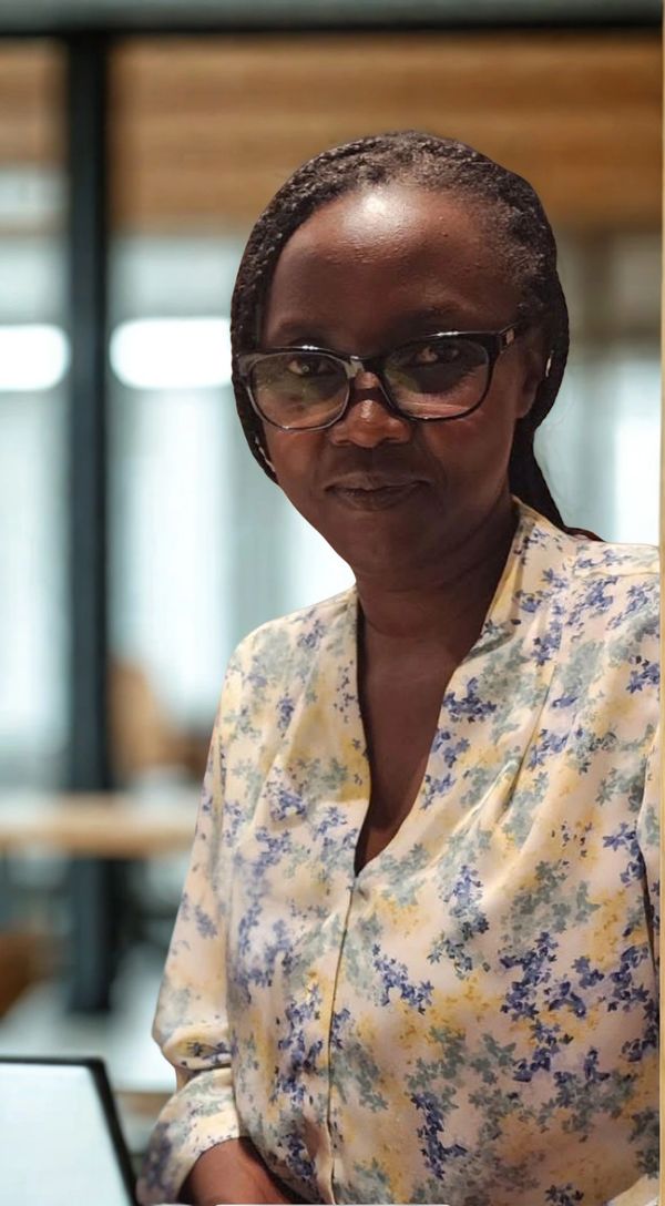 Woman wearing glasses and a floral blouse in a softly lit indoor setting.
