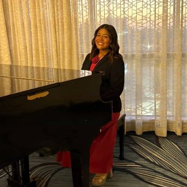 Young woman smiling beside a piano indoors.