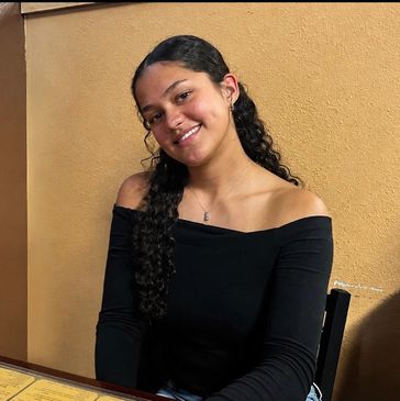 Young woman smiling in a black off-shoulder top.