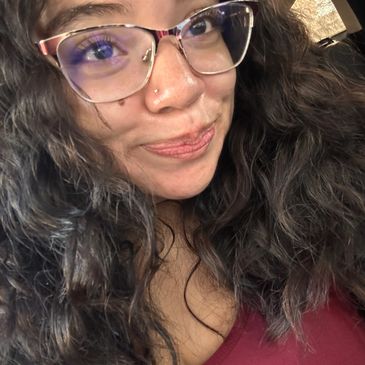 Smiling woman with glasses and curly hair.