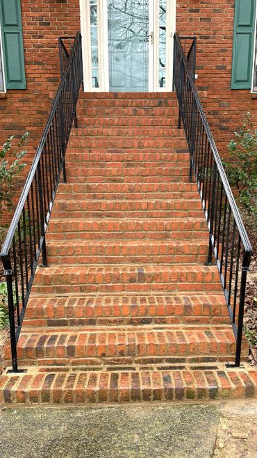 Brick staircase with black metal railings leading to a door.