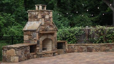Outdoor stone fireplace with string lights.