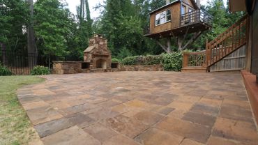 Backyard with stone fireplace and treehouse.
