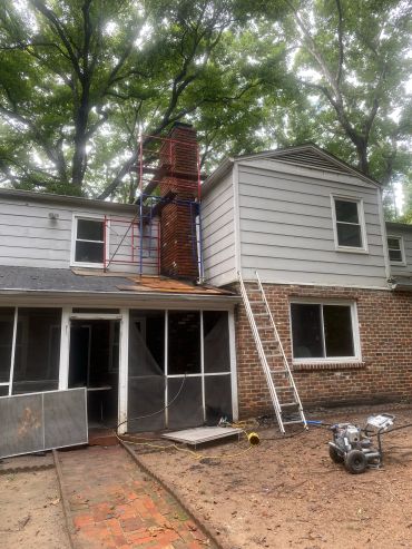 House with chimney repair work and scaffolding on roof.
