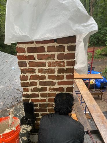 Man working on repairing a brick chimney.