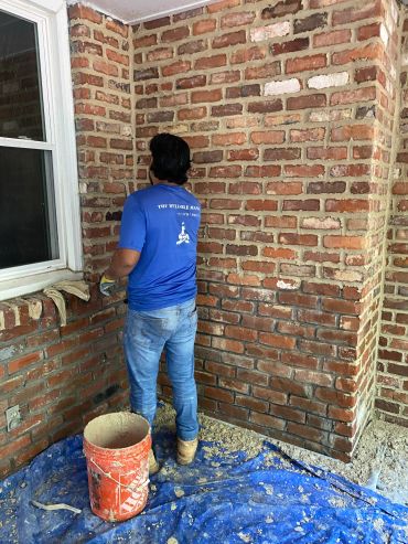 Man working on brick wall construction indoors.