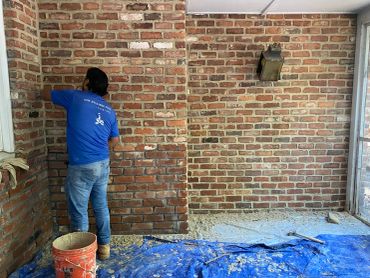 Man working on a brick wall indoors.
