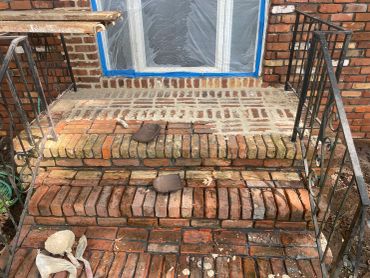 Brick steps being repaired with mortar around a window.
