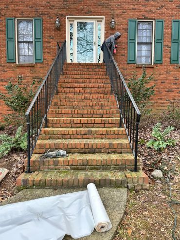 Person standing near entrance at top of brick stairs.