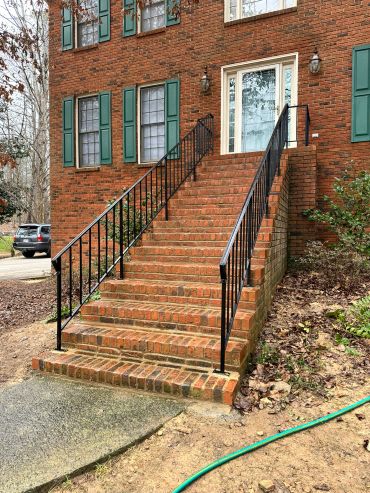 Brick stairway leading to a house entrance with green shutters.