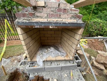Under-construction brick fireplace outdoors.