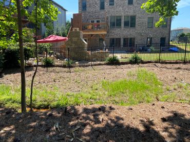 Backyard with stone fireplace and wooden deck on sunny day.