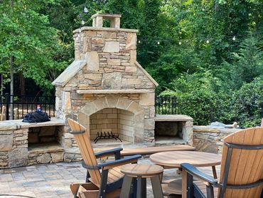 Outdoor stone fireplace with chairs and table.