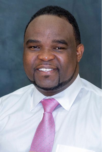 Smiling man in white shirt and pink tie.