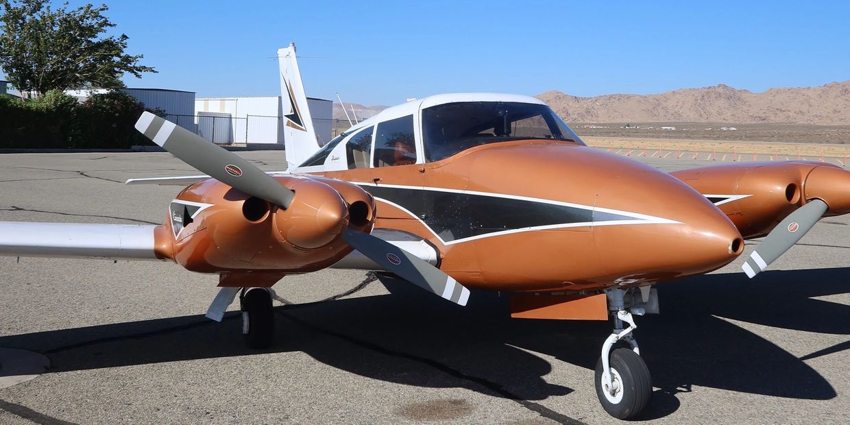 Small twin-engine vintage airplane parked on runway. Piper PA 30 Twin Engine Comanche owned by Tally