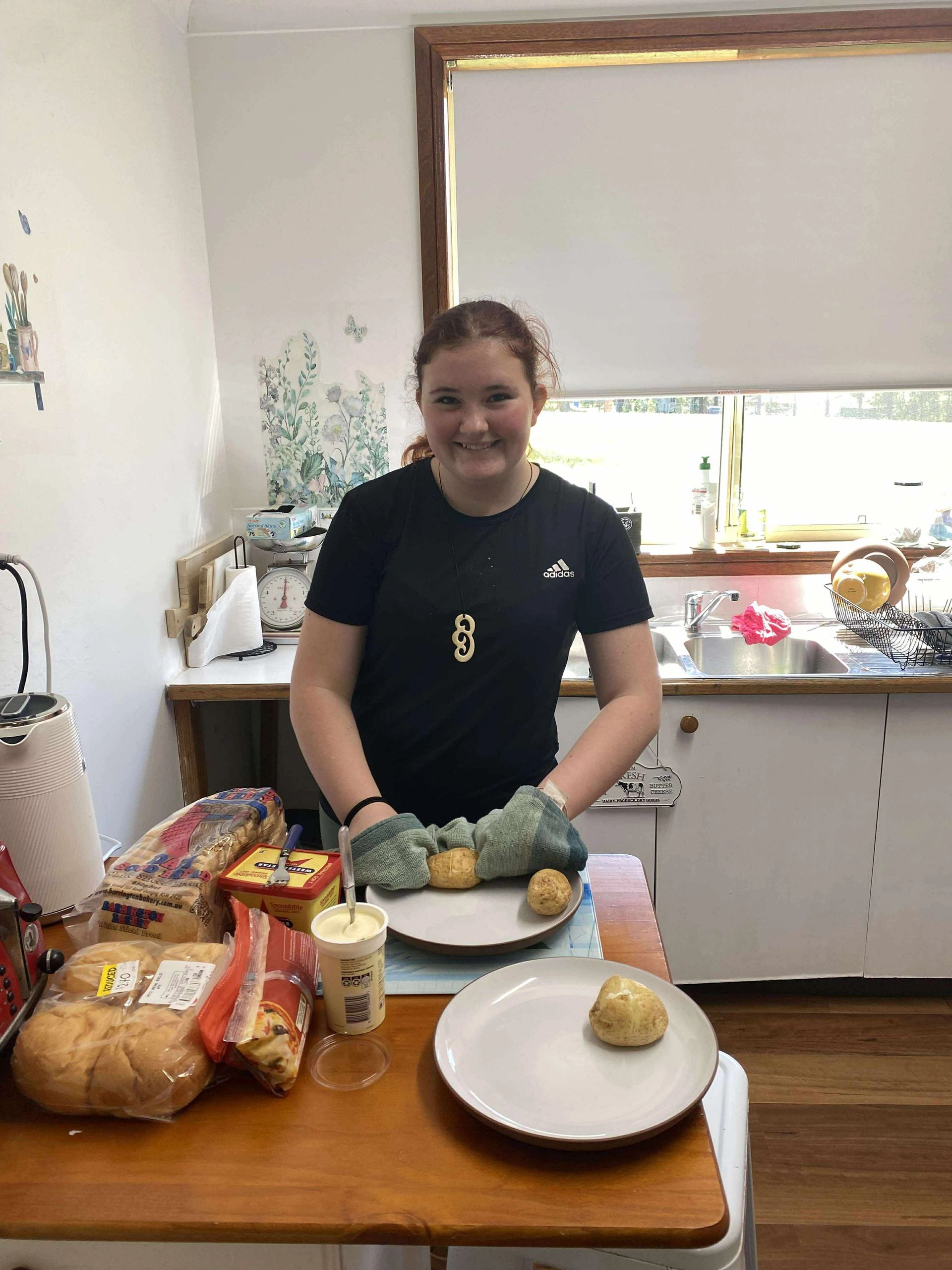 Smiling girl baking in kitchen with gloves.