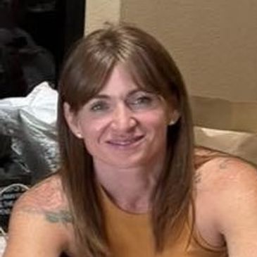 A woman with brown hair smiling indoors.