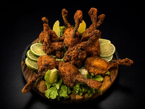 Plate of crispy fried chicken drumettes garnished with lime slices and lettuce.
