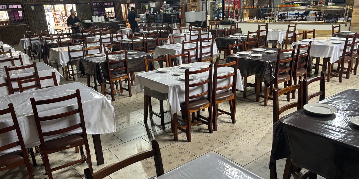 Empty restaurant with neatly arranged tables covered in white and black tablecloths.