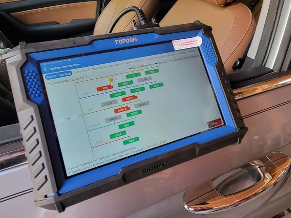 TOPDON diagnostic tool displaying a vehicle system topology on a car door.