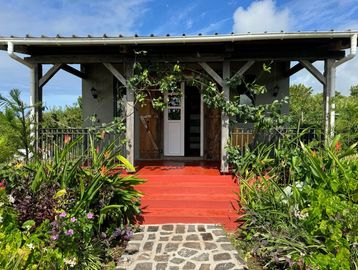 Petite maison avec porche et jardin fleuri.