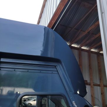 Blue truck cab under a metal roof structure.