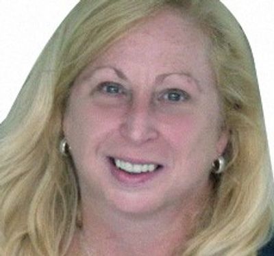 Smiling woman with blonde hair and silver hoop earrings.