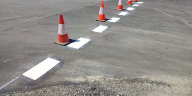 Traffic cones marking freshly painted road lines on asphalt.