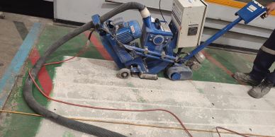 Industrial floor grinding machine in use on a concrete surface.