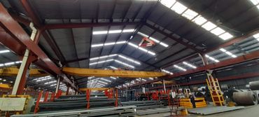 Vista panorámica del interior de una fábrica con vigas y maquinaria.