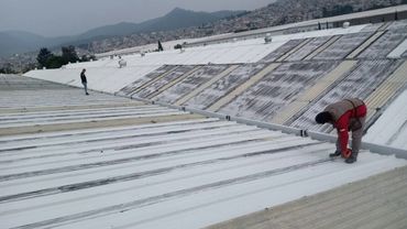 Trabajadores pintan un techo grande de metal.