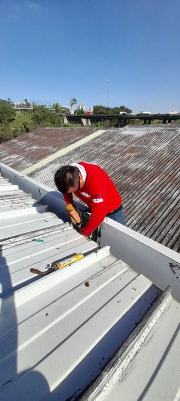 Hombre trabajando en un techo bajo un cielo despejado.